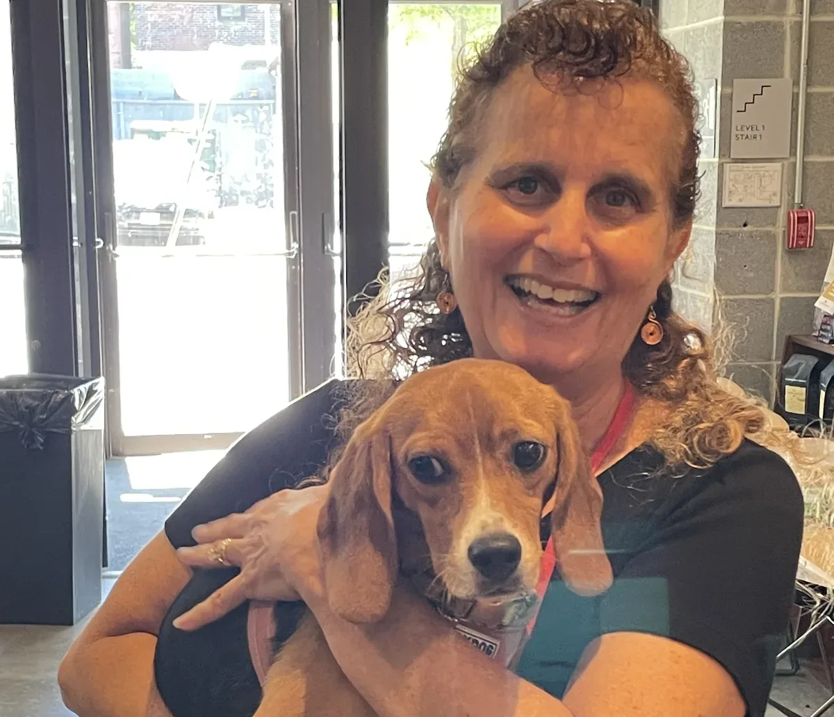 Lynn Max smiling while holding a beagle at an animal rights event